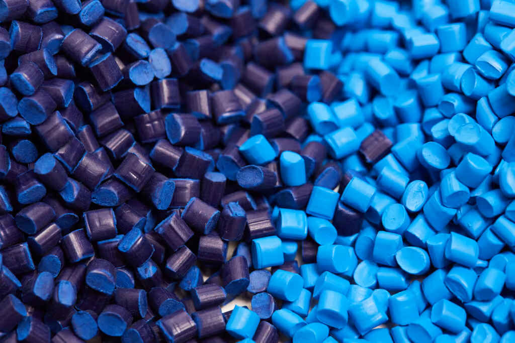 Close-up of small plastic pellets in purple, light blue, dark blue, and yellow colors.