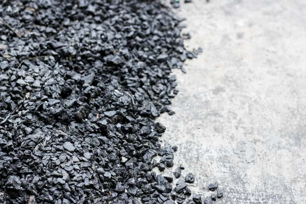 Close-up of black crushed stones or gravel on the left side next to a gray concrete surface.